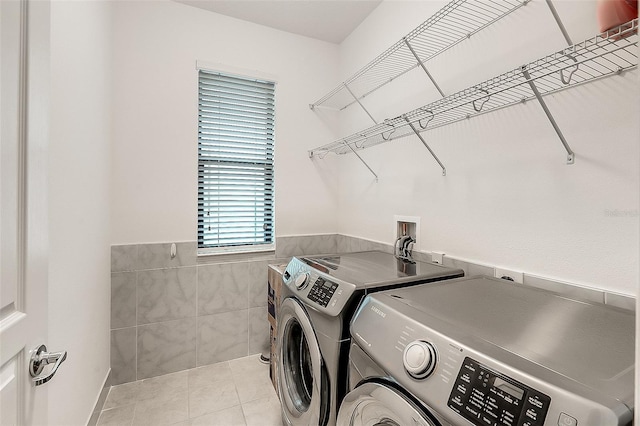 laundry area featuring laundry area, a wainscoted wall, tile walls, tile patterned floors, and washing machine and dryer