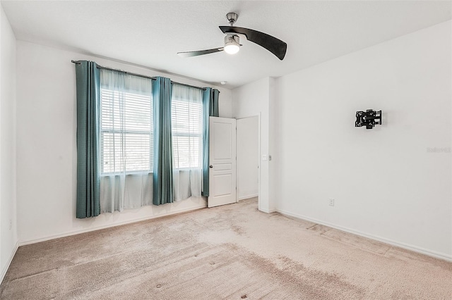 spare room with carpet, baseboards, and ceiling fan