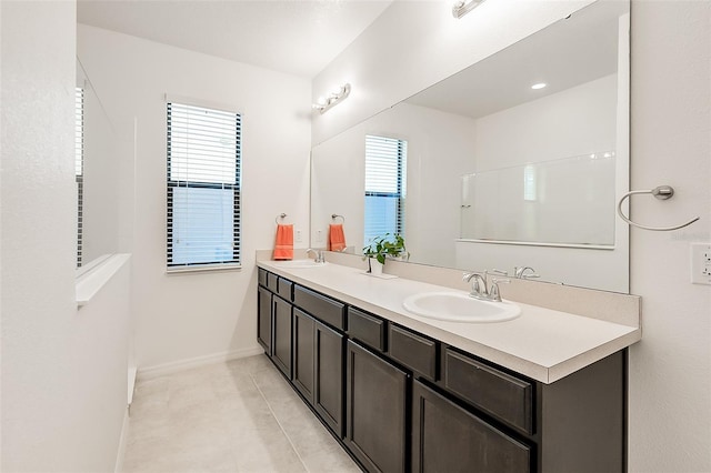 full bathroom with tile patterned flooring, double vanity, baseboards, and a sink