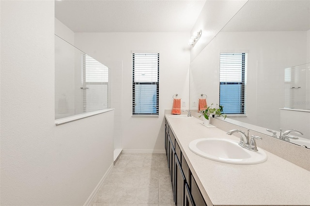 full bath featuring a wealth of natural light, baseboards, a sink, and a walk in shower