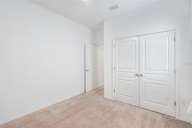 unfurnished bedroom with visible vents, baseboards, a closet, and light carpet