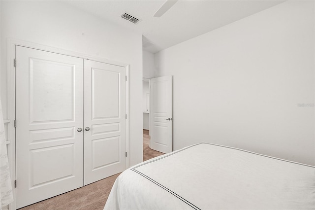 bedroom with light carpet, visible vents, a closet, and ceiling fan