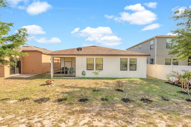 back of house featuring a sunroom, a yard, stucco siding, and fence