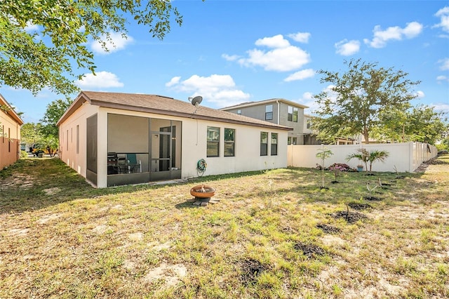 back of property with fence, a sunroom, a lawn, and stucco siding