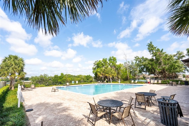 pool with a patio area and fence