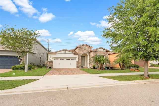 mediterranean / spanish home with stucco siding, stone siding, decorative driveway, an attached garage, and a front lawn
