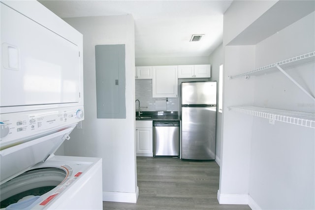 1831 Aaron Ave, Orlando, FL 32811 - clothes washing area featuring stacked washing maching and dryer, a sink, visible vents, laundry area, and wood finished floors