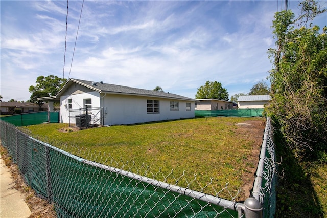 1831 Aaron Ave, Orlando, FL 32811 - rear view of property featuring a fenced backyard, a yard, stucco siding, and central air condition unit