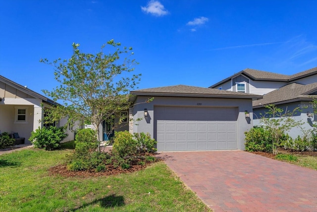 single story home with a front lawn, decorative driveway, a garage, and stucco siding