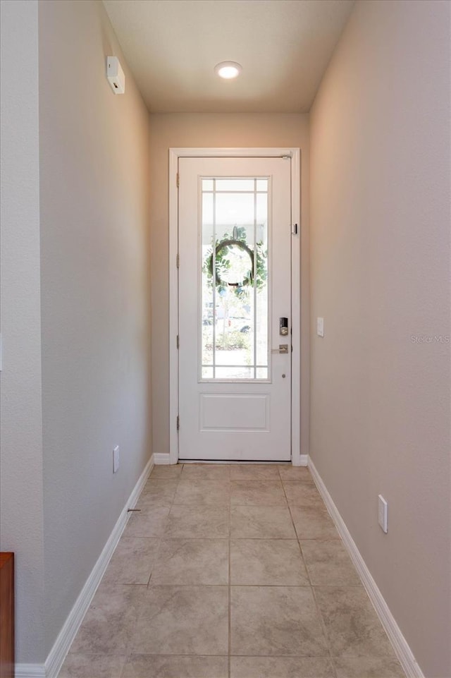 doorway with baseboards and light tile patterned flooring