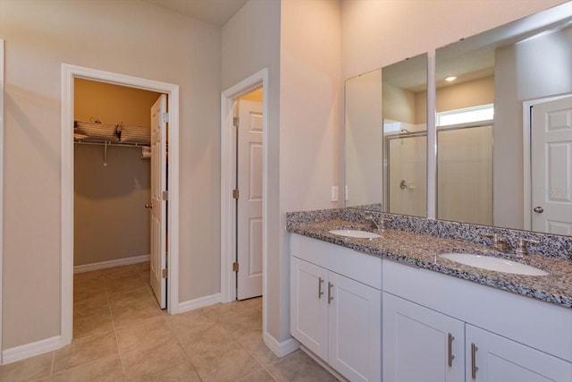 full bath featuring a sink, baseboards, a walk in closet, and a stall shower
