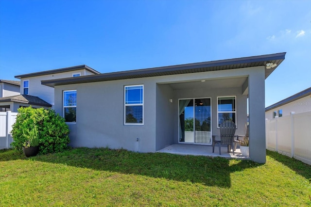 back of property featuring a patio, a yard, stucco siding, and fence