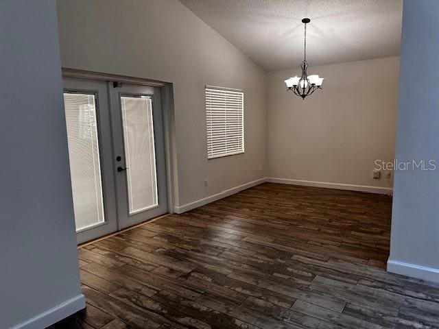unfurnished room with french doors, an inviting chandelier, dark wood-style floors, and lofted ceiling