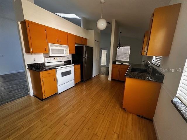 kitchen featuring white appliances, light wood-type flooring, a sink, and dark countertops