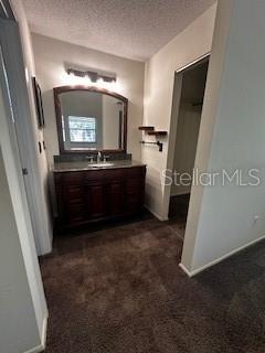 bathroom featuring baseboards, vanity, and a textured ceiling