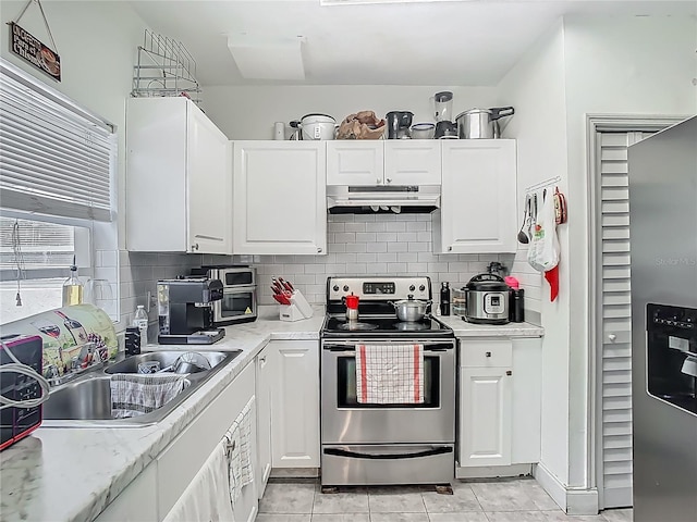 kitchen with light countertops, a sink, under cabinet range hood, stainless steel appliances, and white cabinets