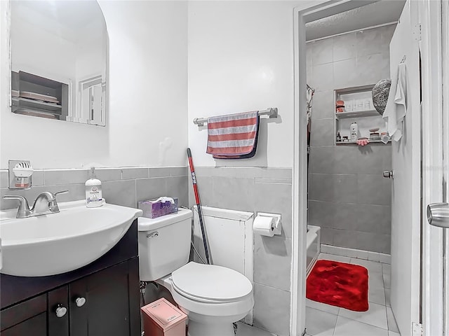 full bath featuring toilet, vanity, wainscoting, walk in shower, and tile walls