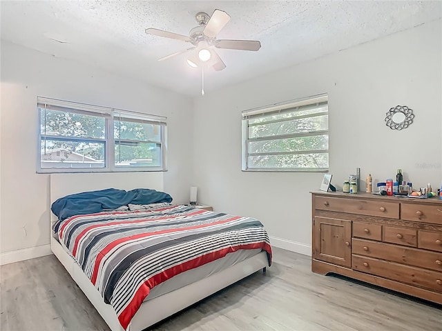 bedroom with baseboards, a textured ceiling, ceiling fan, and wood finished floors