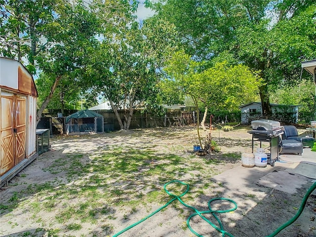 view of yard featuring an outbuilding, fence, and a shed