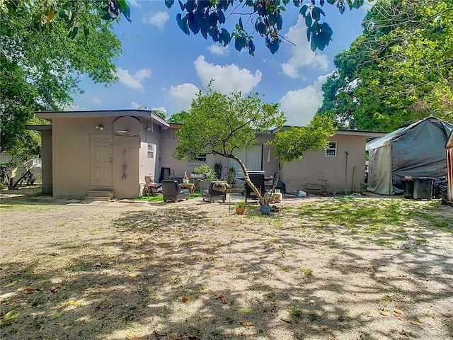 rear view of house featuring a patio, stucco siding, and entry steps