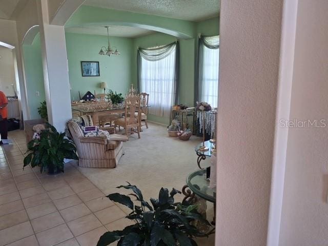 450 Morning Blossom Ln, Oviedo, FL 32765 - tiled living room featuring arched walkways, a chandelier, and a textured wall