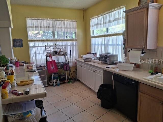 450 Morning Blossom Ln, Oviedo, FL 32765 - kitchen featuring tile counters, a sink, light tile patterned floors, decorative backsplash, and black dishwasher