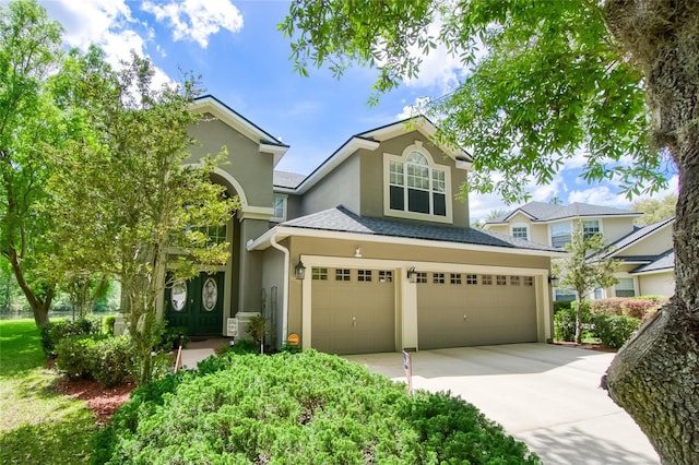 traditional-style home featuring roof with shingles, driveway, stucco siding, and an attached garage