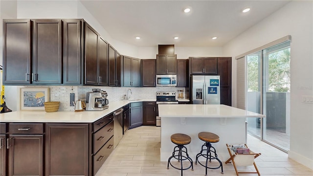 13241 Cormack Ln, Orlando, FL 32827 - kitchen with a breakfast bar area, a center island, decorative backsplash, a sink, and appliances with stainless steel finishes