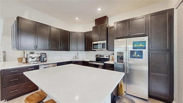 13241 Cormack Ln, Orlando, FL 32827 - kitchen featuring a breakfast bar, a kitchen island, appliances with stainless steel finishes, dark brown cabinetry, and backsplash