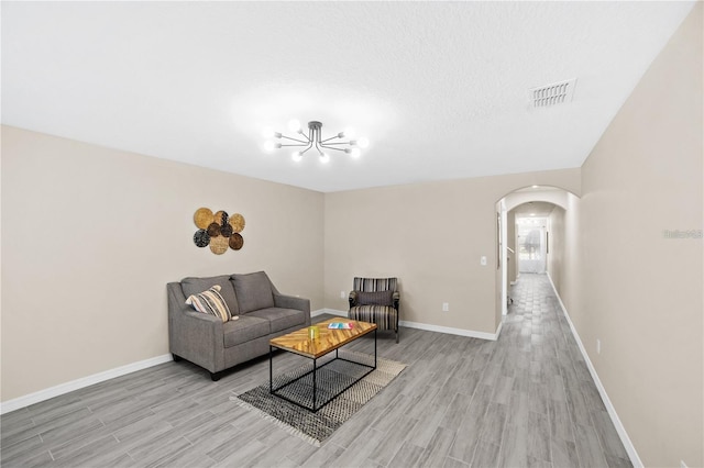 living area featuring baseboards, visible vents, wood finished floors, and arched walkways