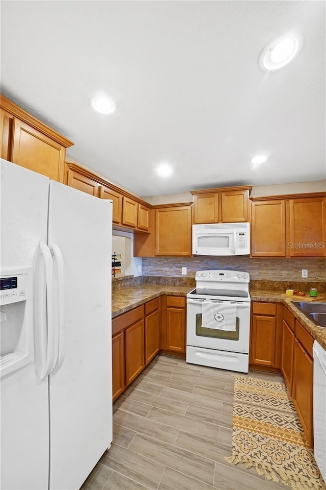 kitchen featuring backsplash, recessed lighting, brown cabinets, and white appliances