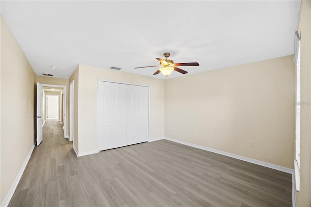 unfurnished bedroom featuring baseboards, visible vents, a closet, and wood finished floors