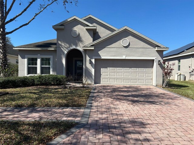 view of front of home with a garage, decorative driveway, and stucco siding