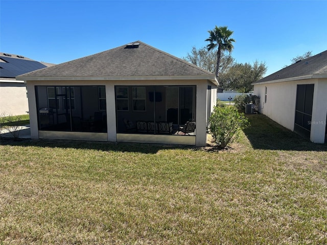 rear view of property with roof with shingles, stucco siding, cooling unit, a sunroom, and a lawn