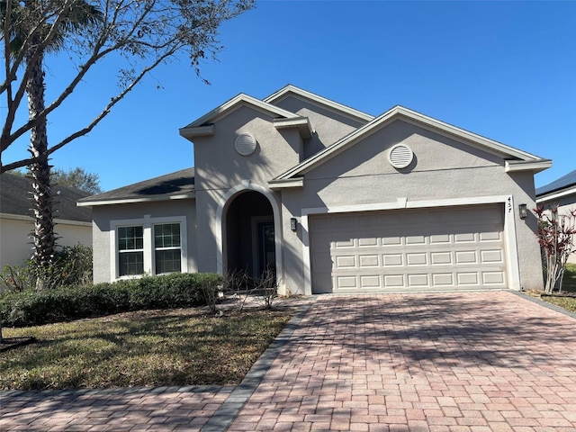 traditional-style home with a garage, stucco siding, and decorative driveway