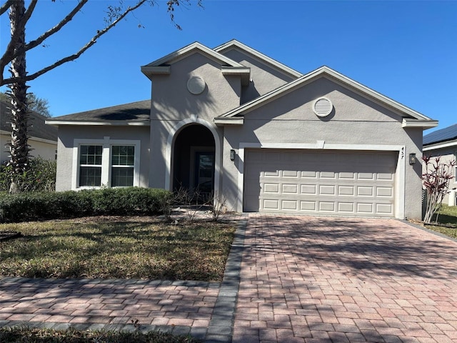 view of front of house with a garage, stucco siding, and decorative driveway