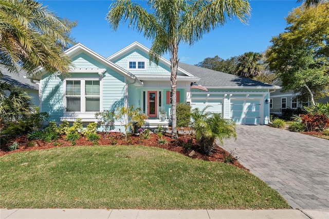 view of front of home with a garage, a front lawn, and decorative driveway