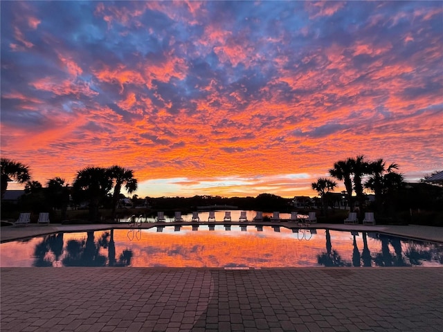 pool at dusk featuring a community pool and a patio area