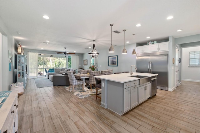 kitchen featuring light countertops, stainless steel appliances, wood finish floors, a sink, and open floor plan