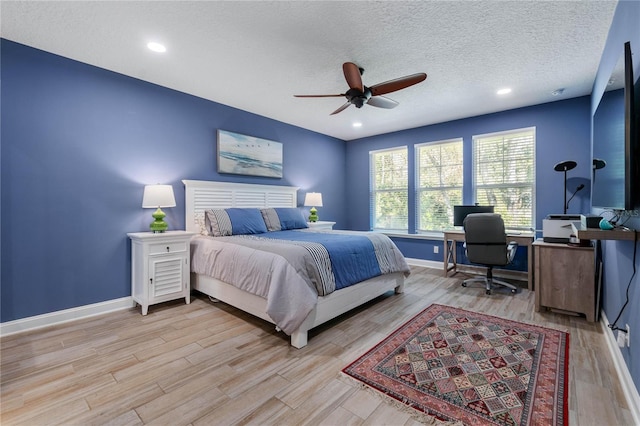 bedroom featuring ceiling fan, baseboards, light wood finished floors, and a textured ceiling