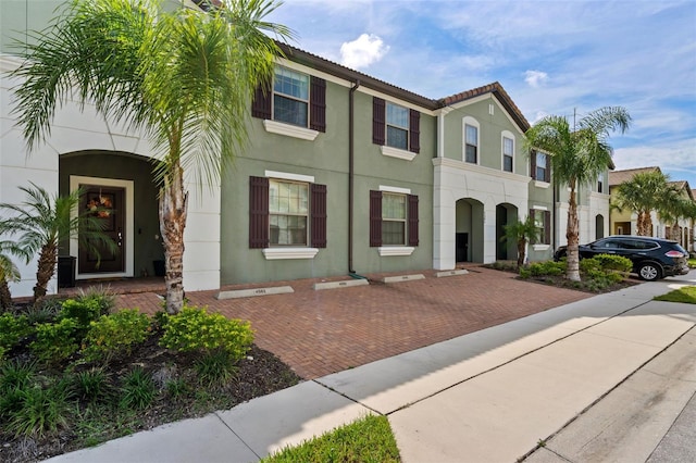 view of front of home featuring a tile roof, decorative driveway, and stucco siding