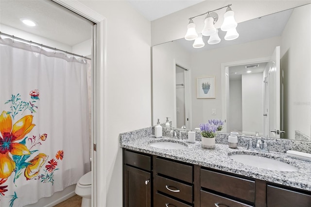 bathroom featuring double vanity, toilet, a sink, and a chandelier
