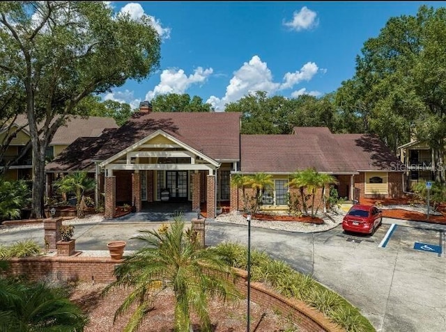view of front of home featuring uncovered parking, a chimney, and brick siding