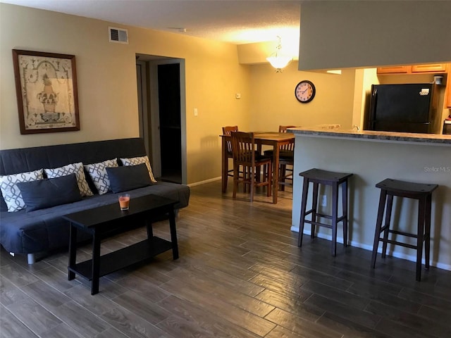 living area with visible vents, baseboards, and dark wood finished floors