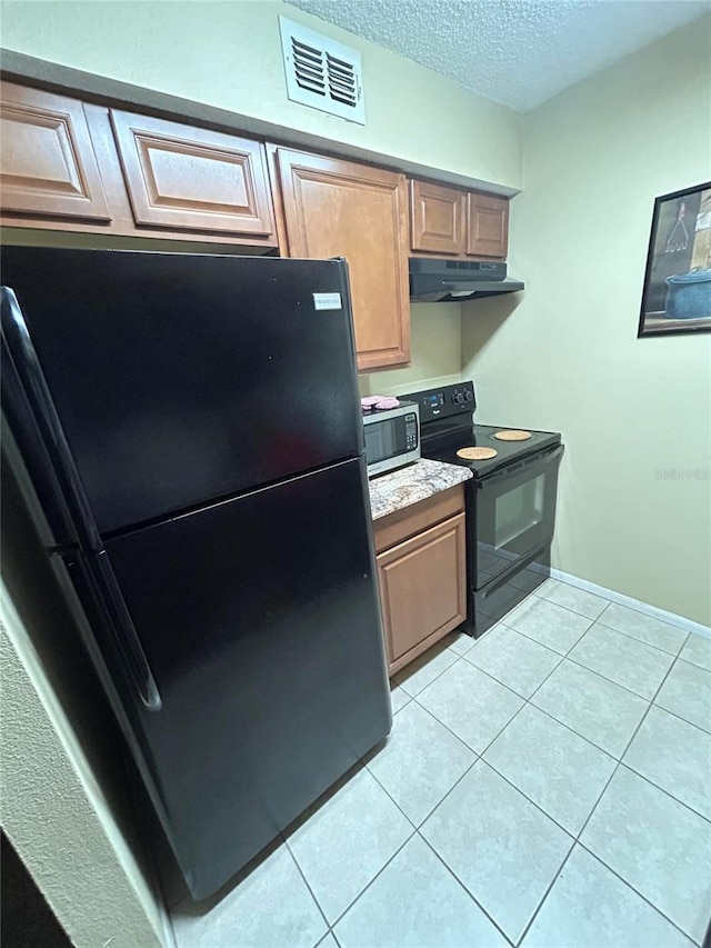 kitchen with visible vents, light tile patterned floors, a textured ceiling, under cabinet range hood, and black appliances