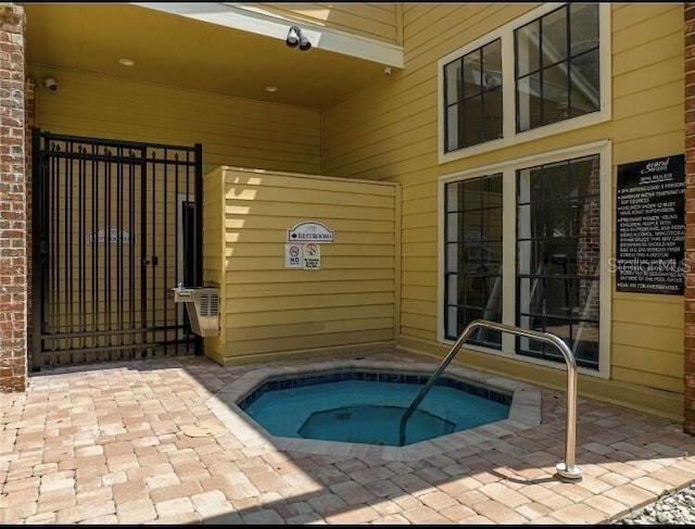 view of swimming pool with a community hot tub and a gate