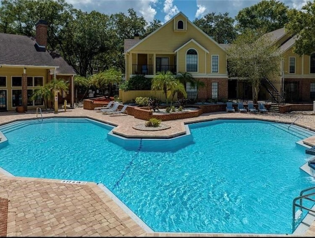 community pool with a jacuzzi and a patio