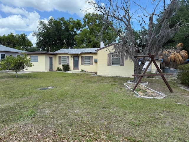 ranch-style home featuring concrete block siding, a front yard, and fence