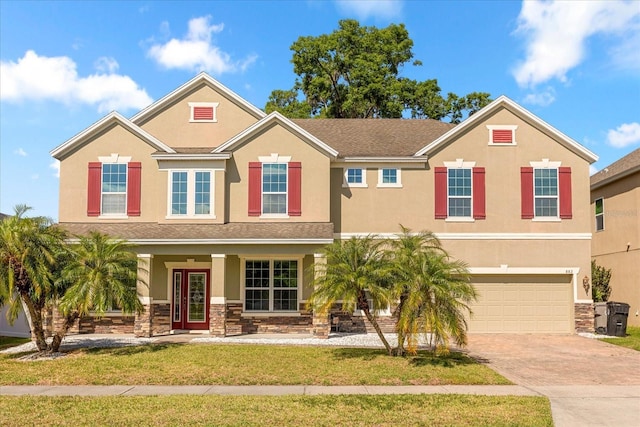 view of front of property with driveway, stucco siding, stone siding, and an attached garage