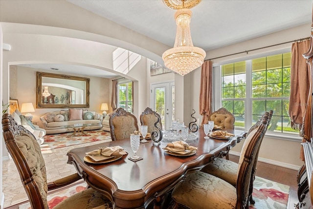 dining space featuring baseboards, a chandelier, visible vents, arched walkways, and wood finished floors
